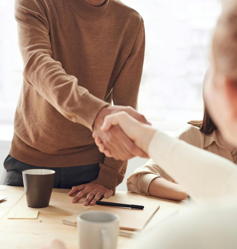 Smiling professionals engage in a welcoming handshake at a business meeting indoors.